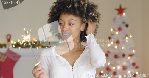 Image of Pretty young woman burning a Christmas sparkler