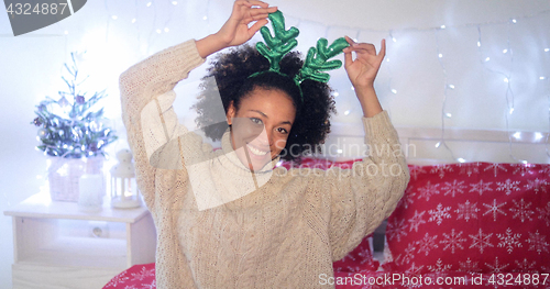 Image of Playful young woman wearing green reindeer antlers