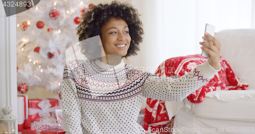 Image of Happy young woman posing for a Christmas selfie