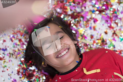 Image of kid blowing confetti while lying on the floor