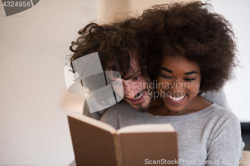 Image of multiethnic couple hugging in front of fireplace