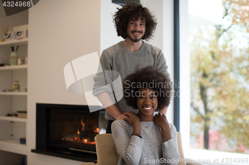 Image of multiethnic couple hugging in front of fireplace