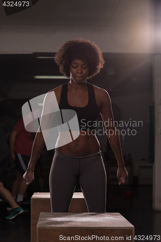 Image of black female athlete is performing box jumps at gym