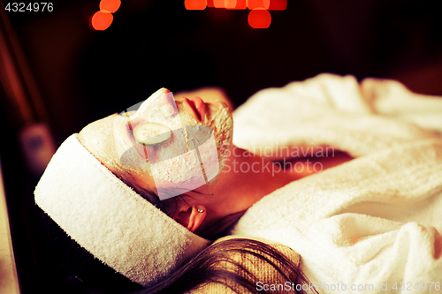 Image of woman is getting facial clay mask at spa