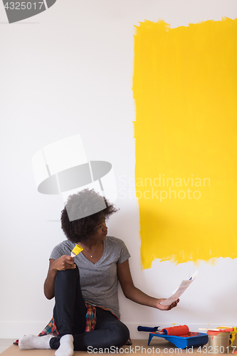 Image of back female painter sitting on floor