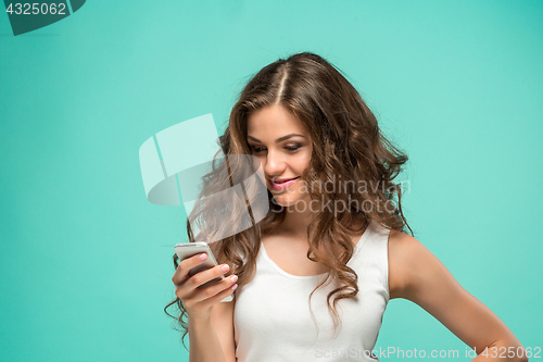 Image of Shocked woman looking at mobile phone on green background