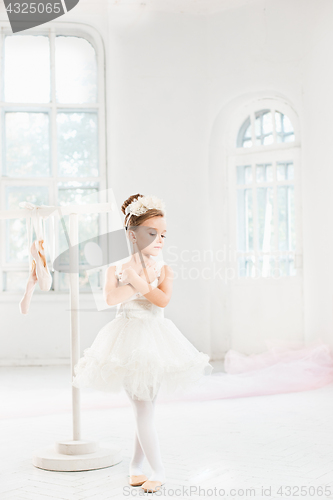 Image of Little ballerina girl in a tutu. Adorable child dancing classical ballet in a white studio.