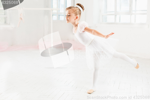 Image of Little ballerina girl in a tutu. Adorable child dancing classical ballet in a white studio.