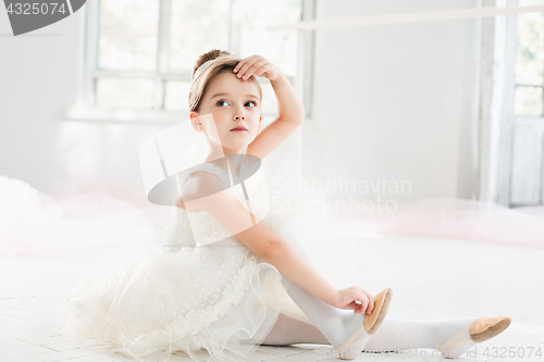Image of The little balerina in white tutu in class at the ballet school