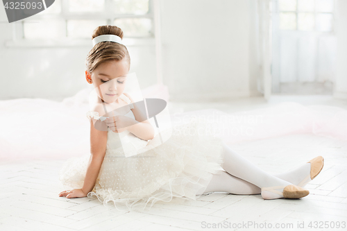 Image of The little balerina in white tutu in class at the ballet school