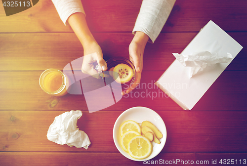 Image of ill woman drinking tea with lemon and ginger