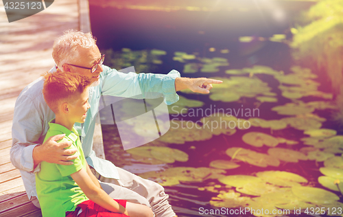 Image of grandfather and grandson sitting on river berth