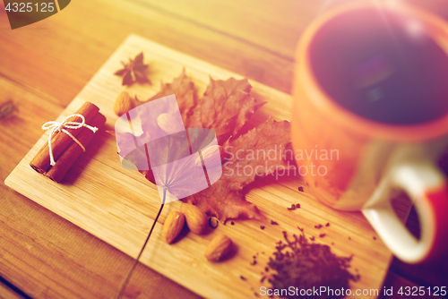 Image of cup of tea, maple leaf and almond on wooden board