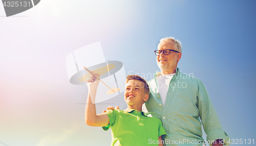 Image of senior man and boy with toy airplane over sky