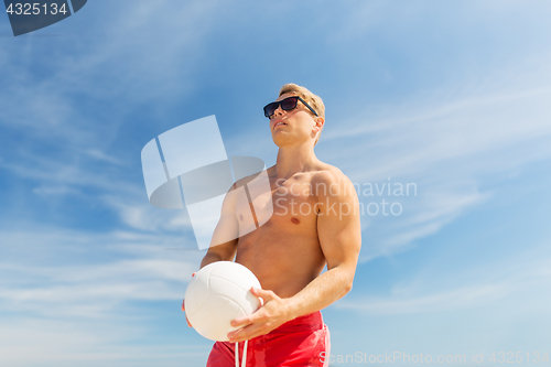 Image of young man with ball playing volleyball on beach