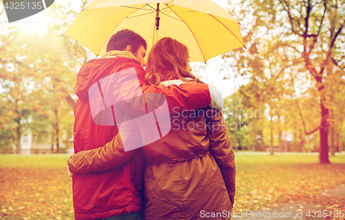 Image of happy couple with umbrella walking in autumn park