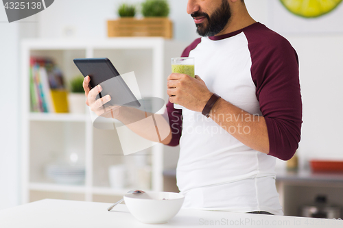Image of man with tablet pc having breakfast at home