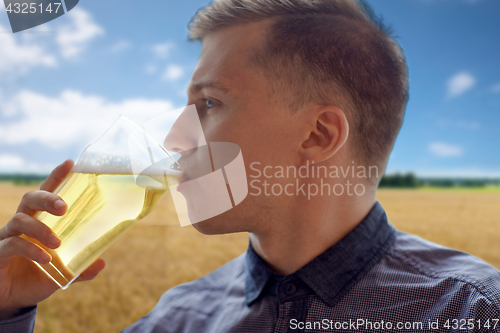 Image of close up of young man drinking beer from glass