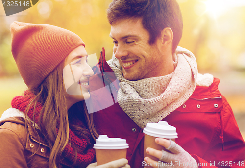 Image of happy couple with coffee walking in autumn park