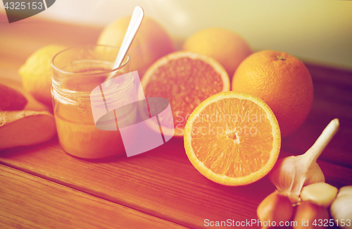 Image of honey, citrus fruits, ginger and garlic on wood