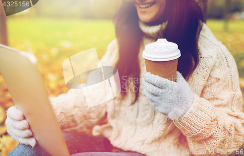 Image of woman with tablet pc and coffee cup in autumn park