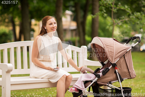 Image of happy mother with smartphone and stroller at park