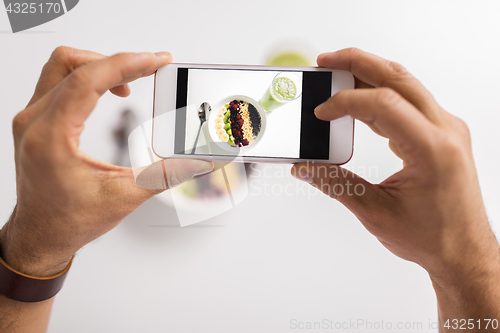 Image of man photographing healthy breakfast by smartphone
