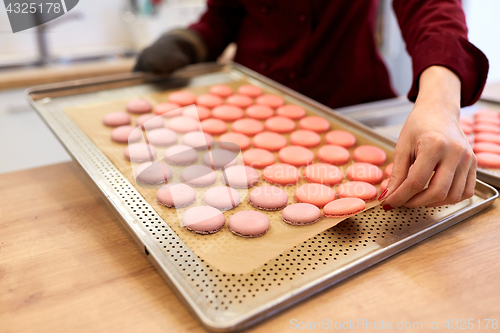 Image of chef with macarons on oven tray at confectionery