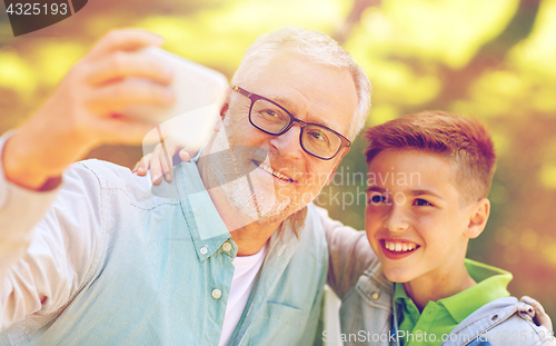 Image of old man and boy taking selfie by smartphone