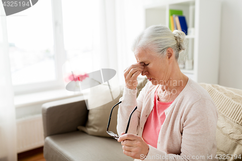 Image of senior woman with glasses having headache at home