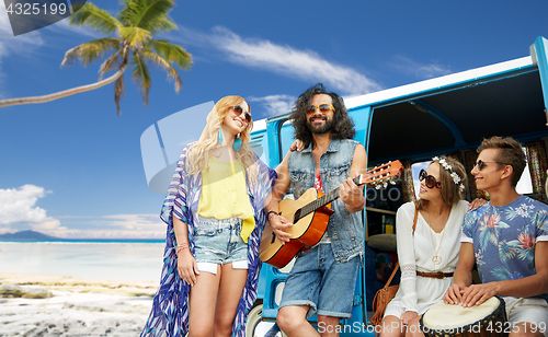 Image of hippie friends playing music over minivan on beach