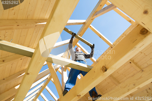 Image of Builder at work with wooden roof construction.