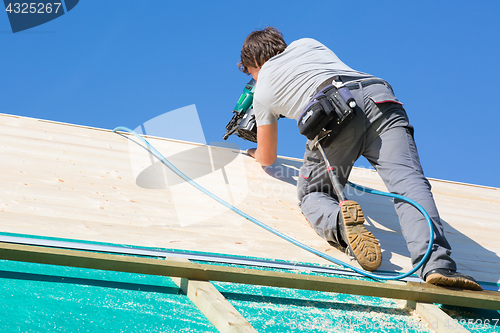 Image of Builder at work with wooden roof construction.