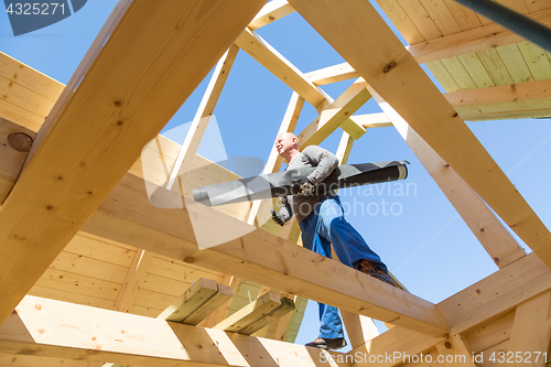 Image of Builder at work with wooden roof construction.