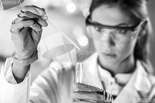 Image of Young scientist pipetting in life science laboratory.