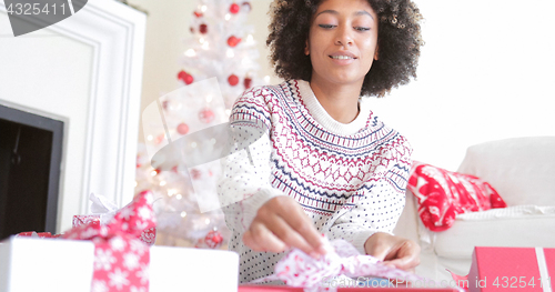 Image of Young woman opening her Christmas gifts