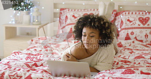 Image of Beautiful woman reading something on laptop in bed