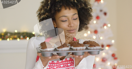 Image of Smiling happy woman with tray of fresh muffins