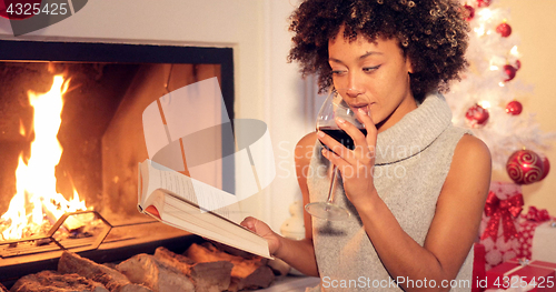 Image of Young woman relaxing with a book and red wine