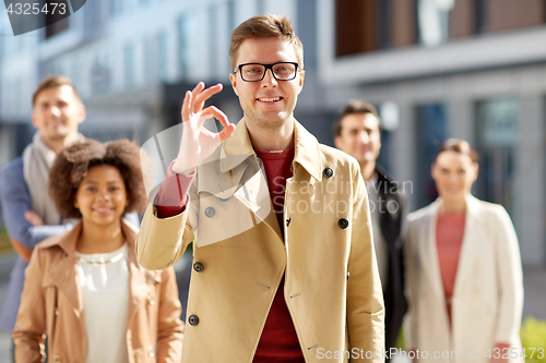 Image of happy smiling man showing ok hand sign outdoors