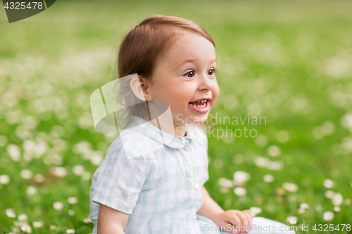 Image of happy baby girl on green summer field