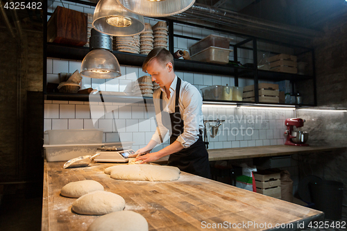 Image of baker portioning dough with bench cutter at bakery