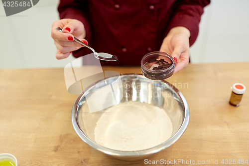 Image of chef hands adding food color into bowl with flour