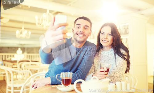 Image of couple taking smartphone selfie at cafe restaurant