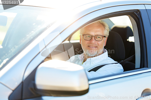 Image of happy senior man driving car with open window