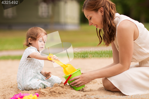 Image of happy mother with baby girl playing in sandbox