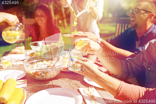 Image of happy friends with drinks at summer garden party