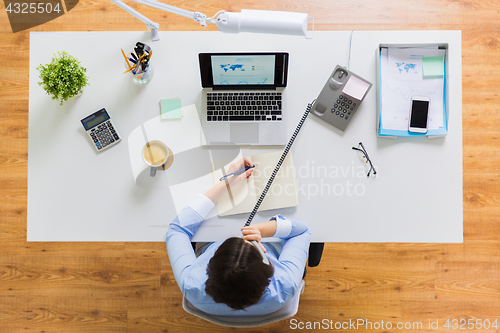 Image of businesswoman calling on phone at office table