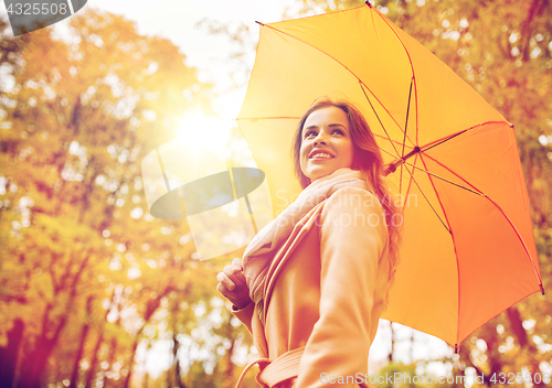 Image of happy woman with umbrella walking in autumn park