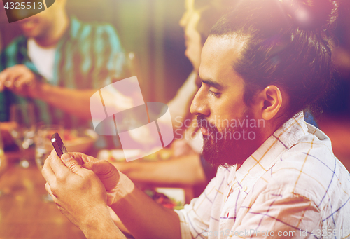 Image of man with smartphone and friends at restaurant